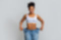Successful weight loss, afro woman with too large jeans after effective diet, grey backgro